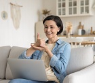 Happy friendly mature therapist woman talking on video call at home, using sign language, speaking to patient with hearing disability, deafness, showing gestures at laptop screen, smiling, laughing